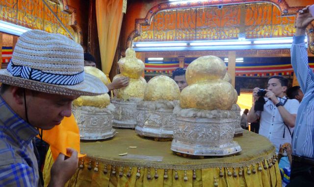 Temple on Inle Lake, people add gold leaf to statues that once were Buddhas.